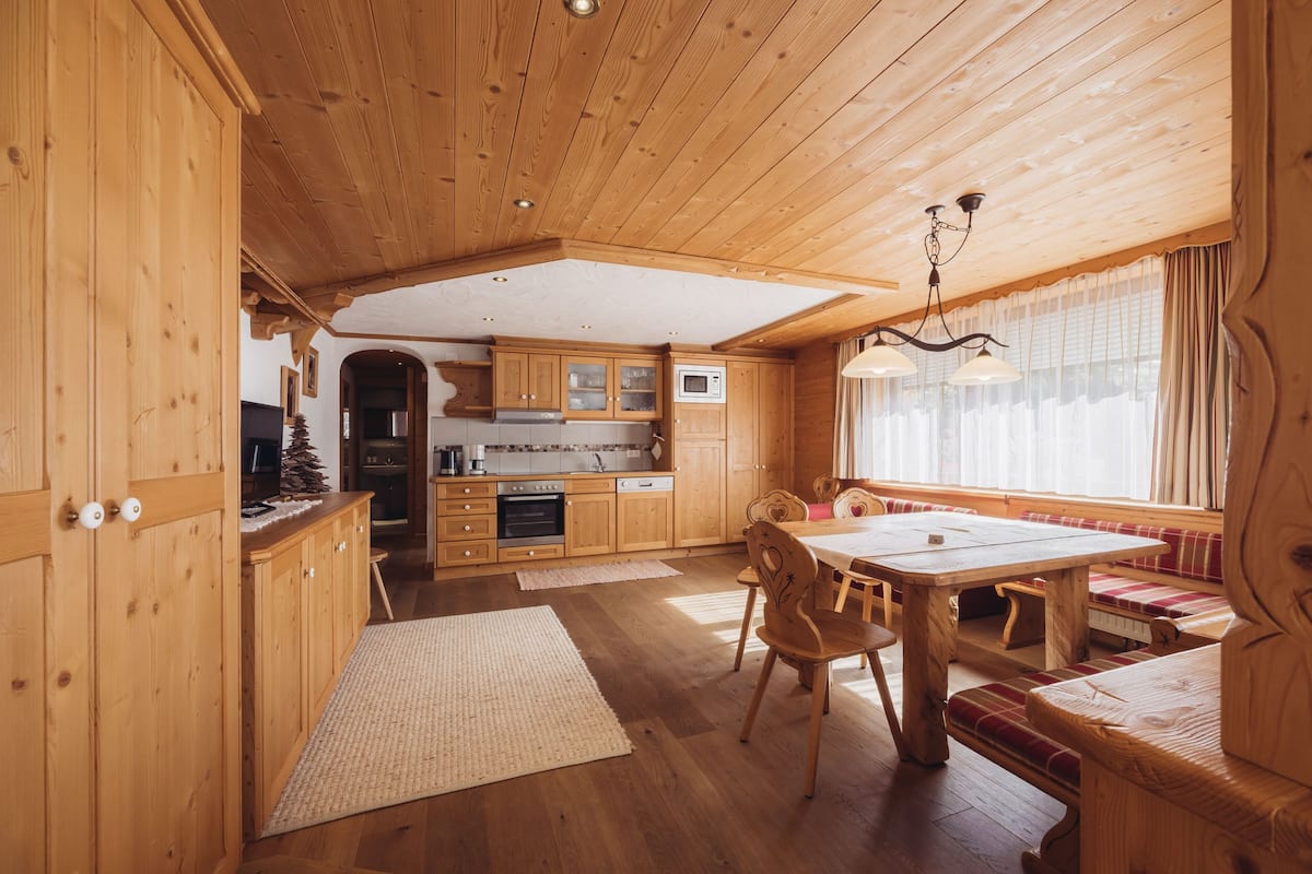Interior de una cabaña de madera con cocina, comedor y zona de estar.