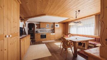 Interior de uma cabana de madeira com cozinha, área de refeições e assentos.