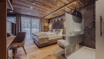 Un dormitorio moderno con techo de madera, cabina de ducha de vidrio y una cama grande con cabecera.