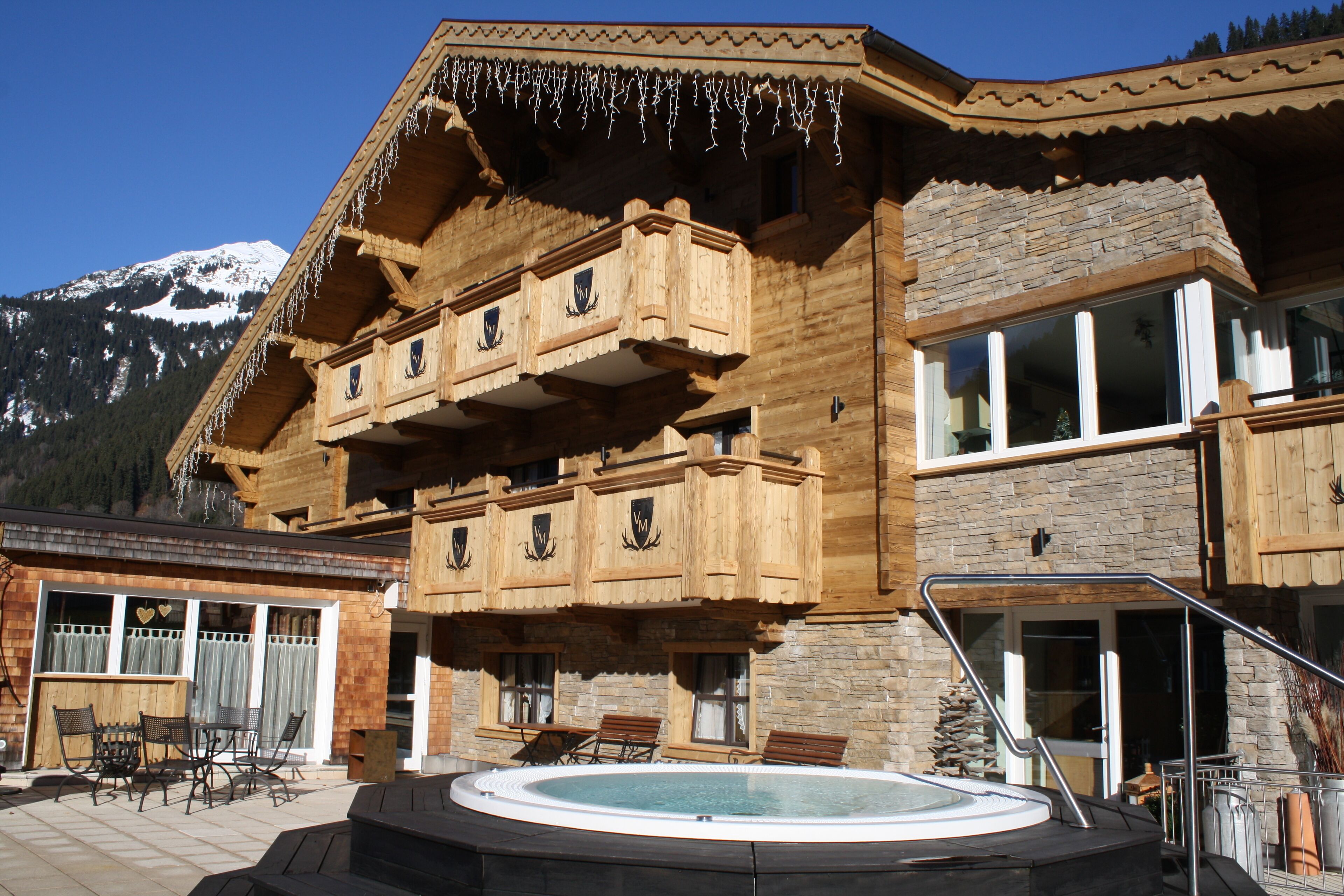 A wooden chalet with a balcony, a hot tub, and a mountain view.