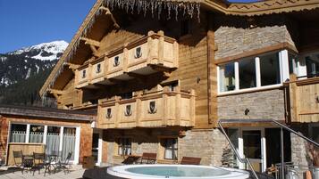 A wooden chalet with a balcony, a hot tub, and a mountain view.