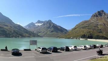Un área de estacionamiento con vehículos y vistas a montañas y un lago.