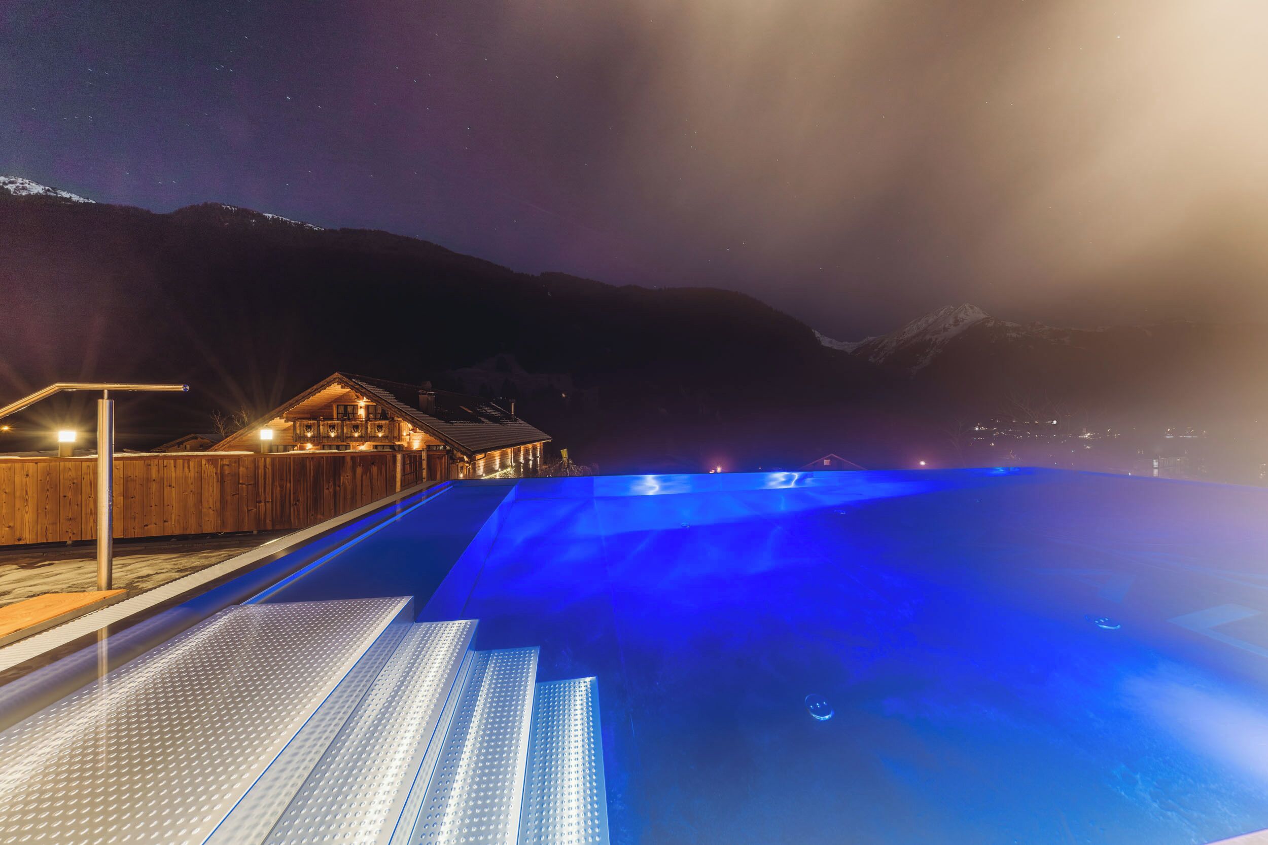 A swimming pool with a wooden deck and a building in the background.