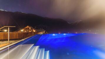 A swimming pool with a wooden deck and a building in the background.