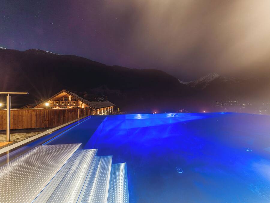 A swimming pool with a wooden deck and a building in the background.