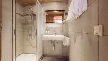 Een moderne badkamer met een douchecabine, een wastafel met spiegel erboven en een handdoek aan de muur.