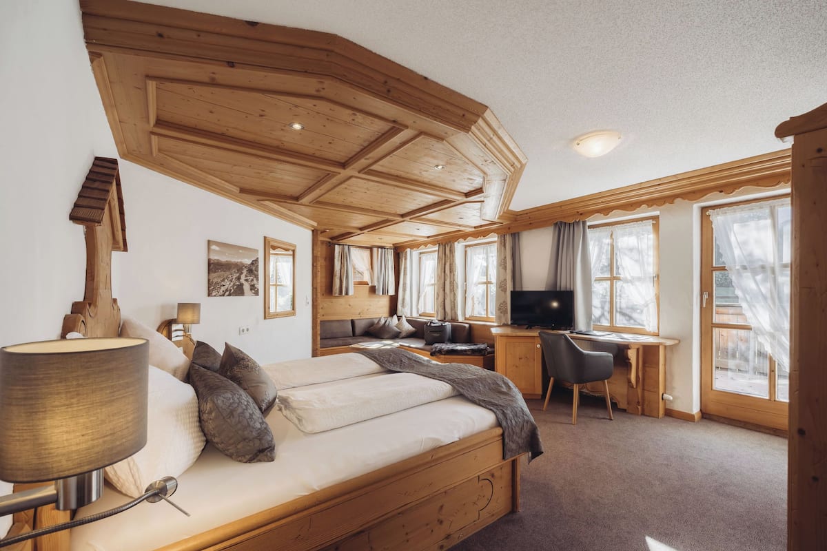 Un dormitorio con cama de madera, un escritorio y una televisión.