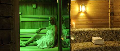 A sauna room with a wooden bench, a bench with a towel, and a wall-mounted clock.