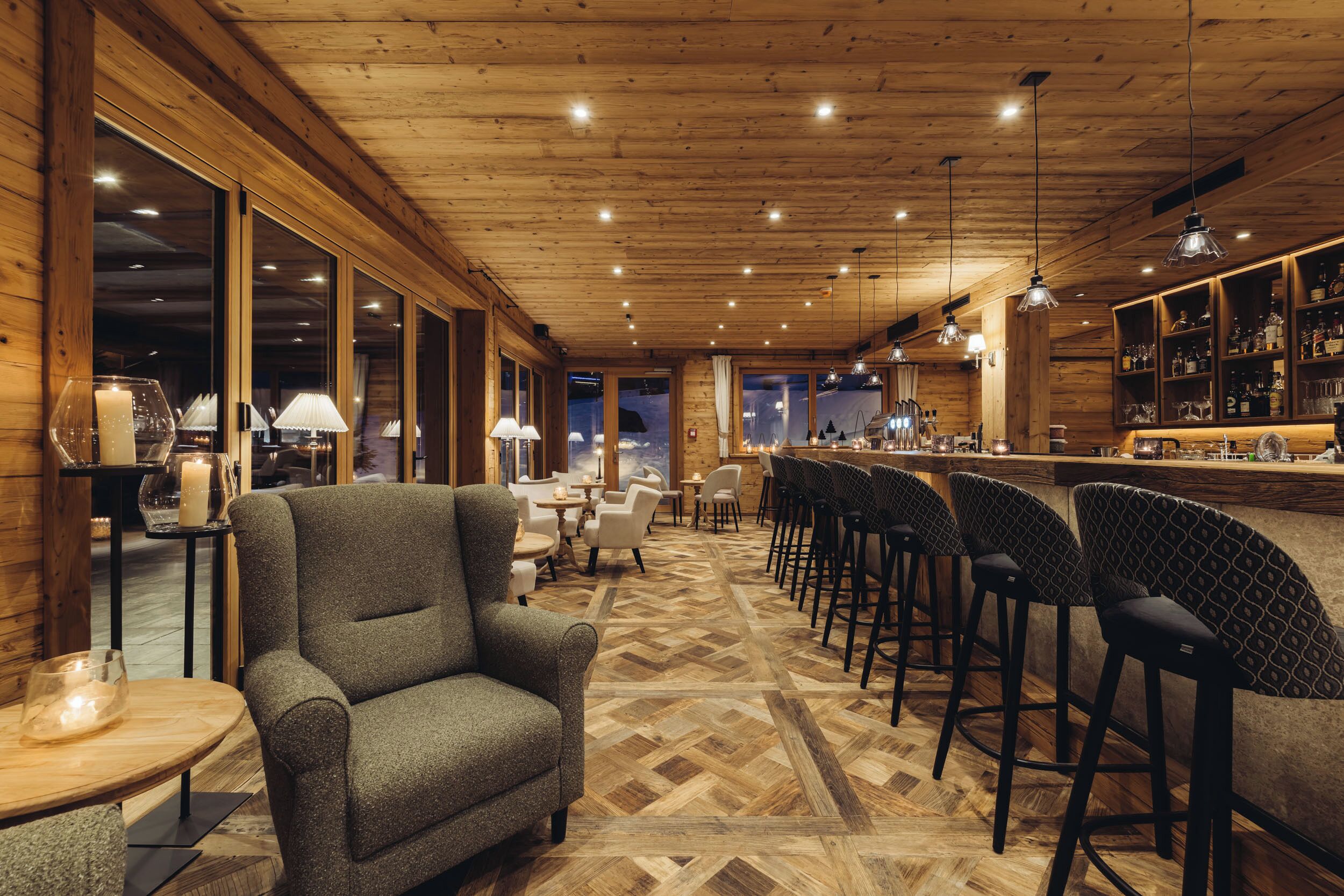 Un rincón de bar acogedor con paredes de madera, suelo de espiga y una barra con taburetes.