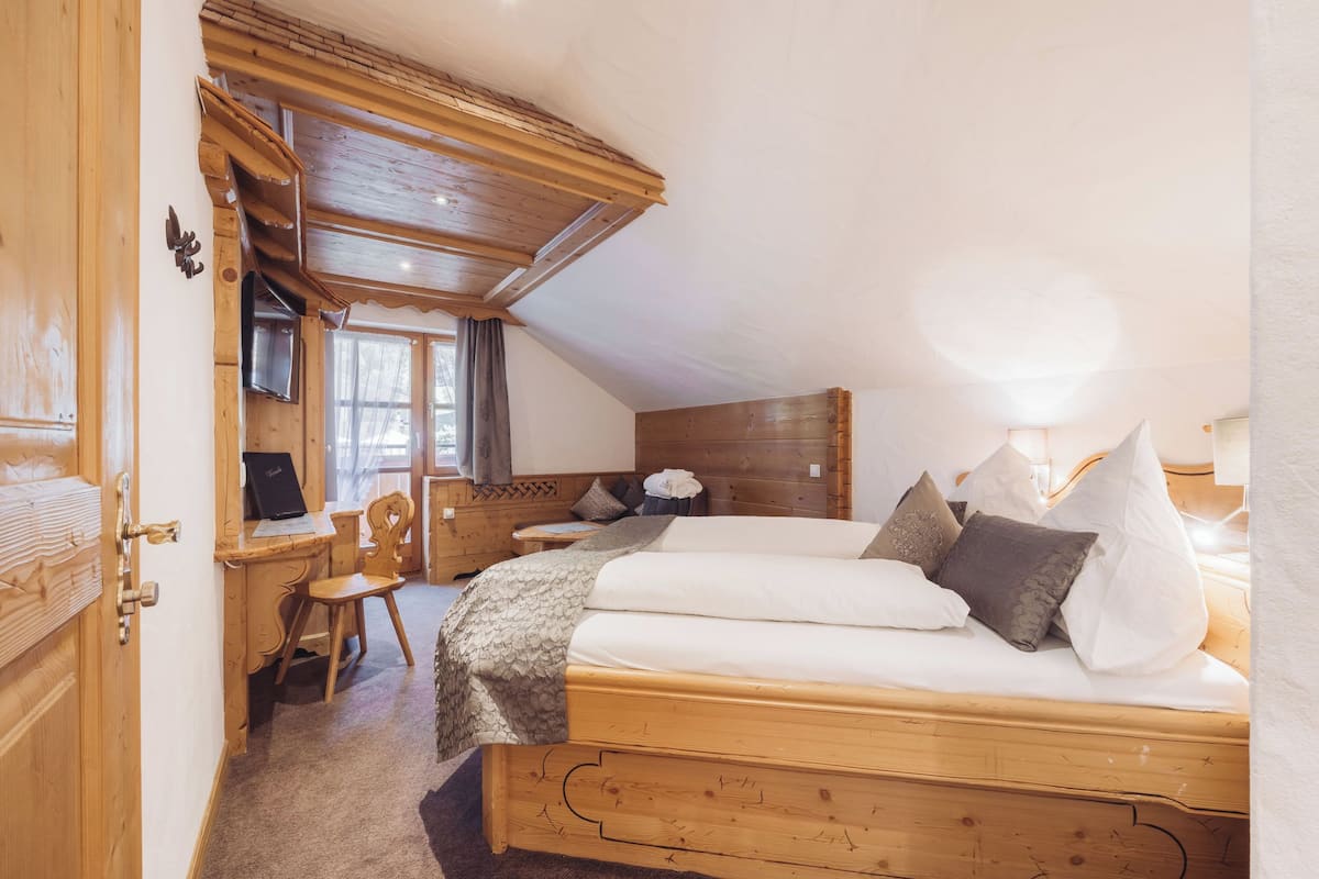 Un dormitorio de madera con cama, escritorio y silla.