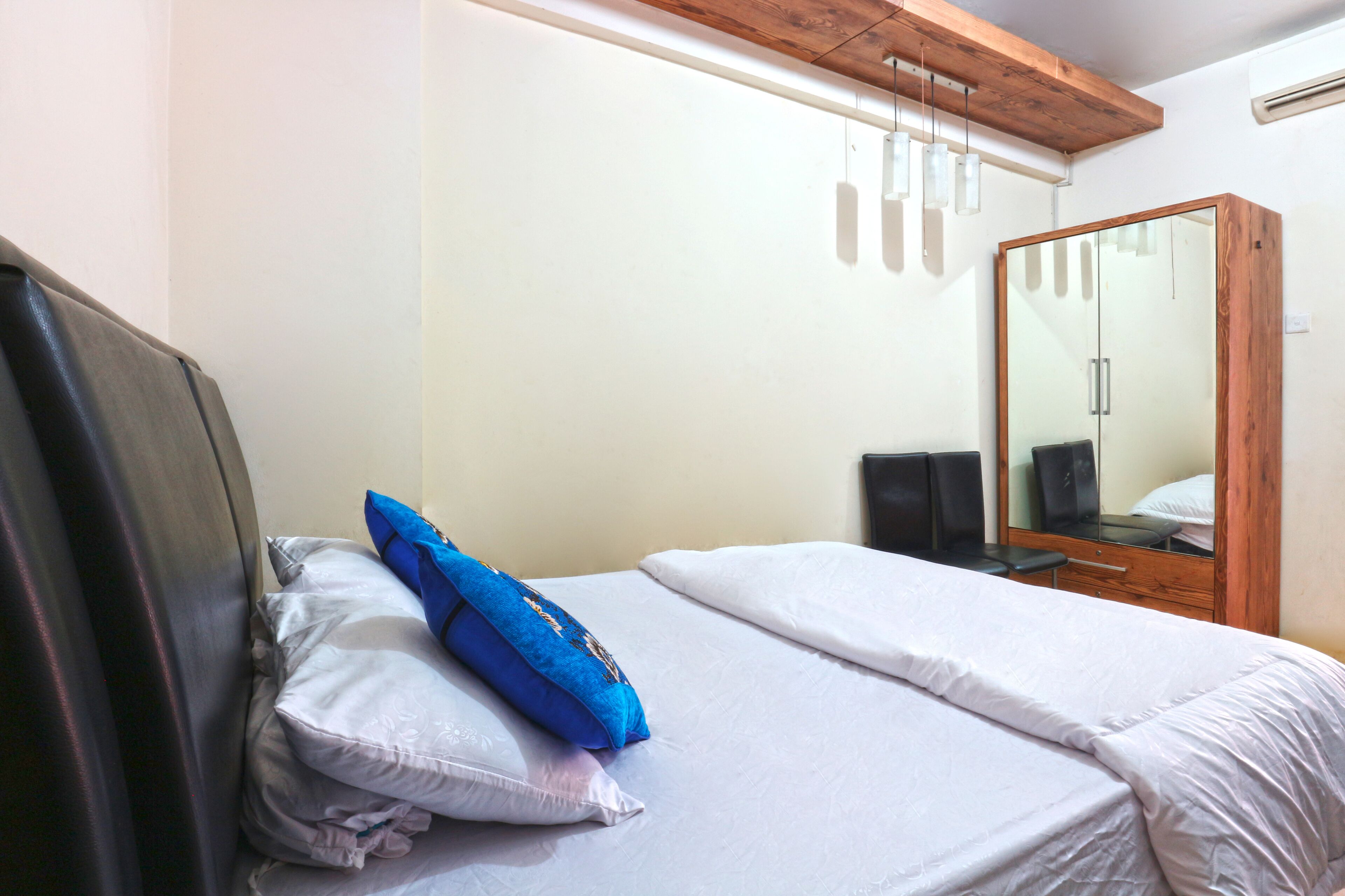A bedroom with a bed, a wooden wardrobe, and a mirror.