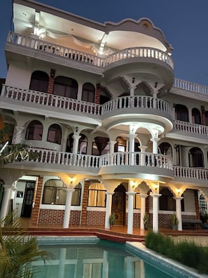 Um edifício com várias andares, varandas, piscina e fachada de tijolos.