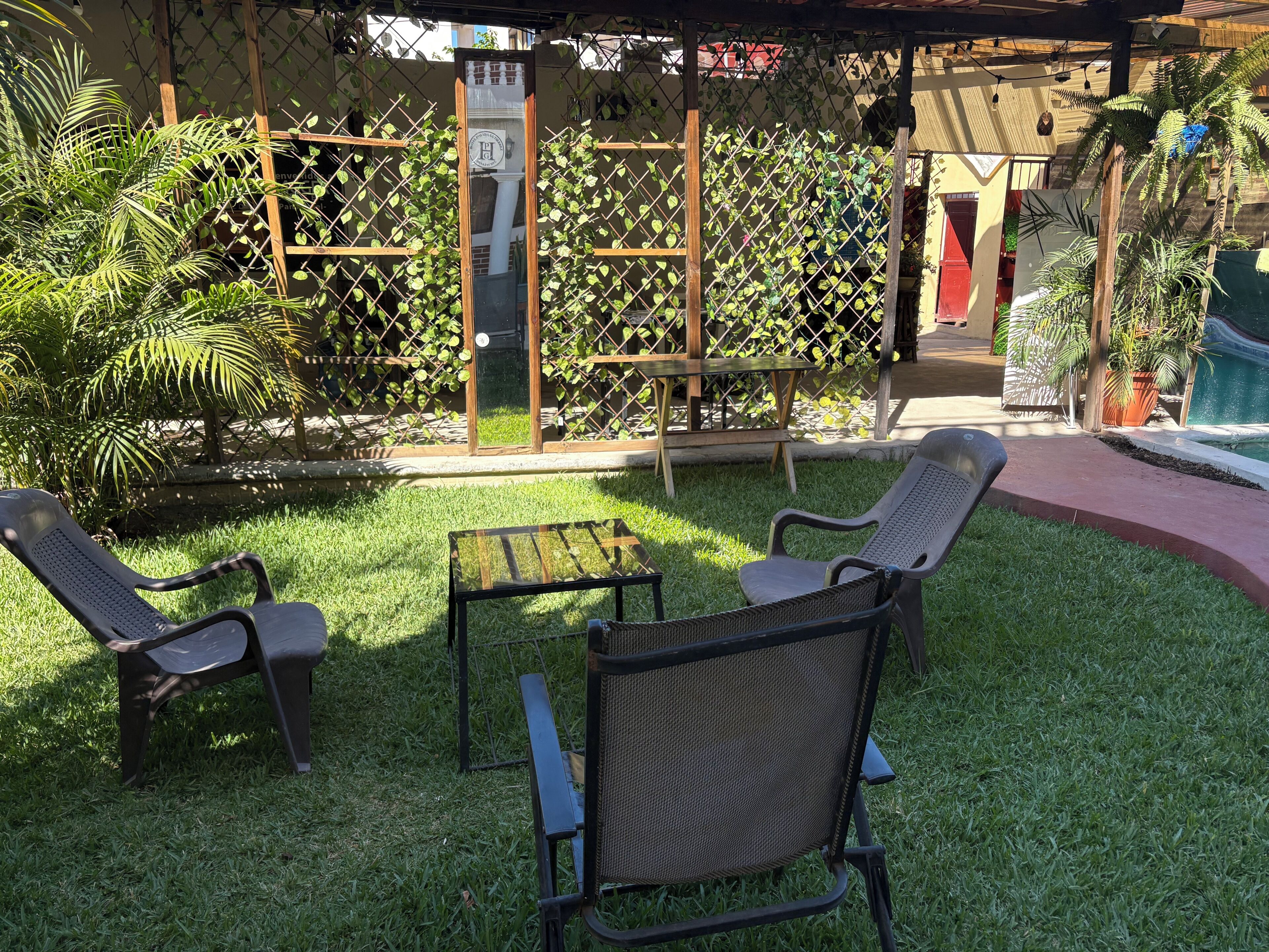 Un espace extérieur aménagé avec deux chaises et une table, entouré d’une clôture en bois et de verdure.