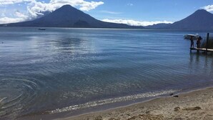 A calm lake with mountains in the background and a boat on the water. - Hotel Posada Gutierrez (Panajachel)