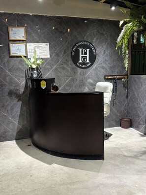 A reception desk with a logo, framed certificates, and a plant. - Hotel Posada Gutierrez (Panajachel)