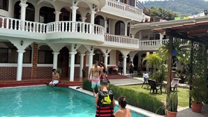 A multi-story building with a swimming pool, outdoor seating, and potted plants. - Hotel Posada Gutierrez (Panajachel)
