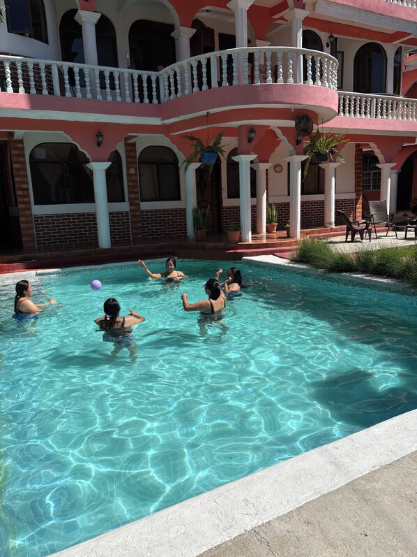 A swimming pool with clear water, surrounded by a building with balconies and columns. - Hotel Posada Gutierrez (Panajachel)