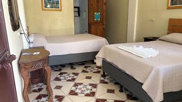 Habitación de hotel con dos camas, una mesita de noche de madera, piso de baldosas y puerta que da a un baño.