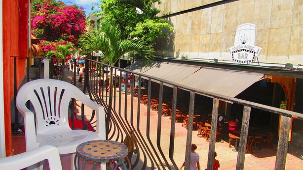 A terrace with outdoor seating, a bar, and a view of a building with a sign.