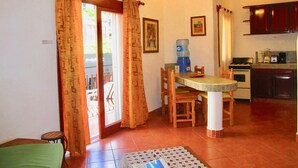 A dining area with a table, chairs, a water dispenser, and a ceiling fan.