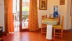 A dining area with a table, chairs, a water dispenser, and a sliding glass door leading to an outdoor patio.