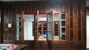 A room with wooden paneling, a table with items on it, and a window with a view of the outside. - Pumaka Resort (Nong Hong)