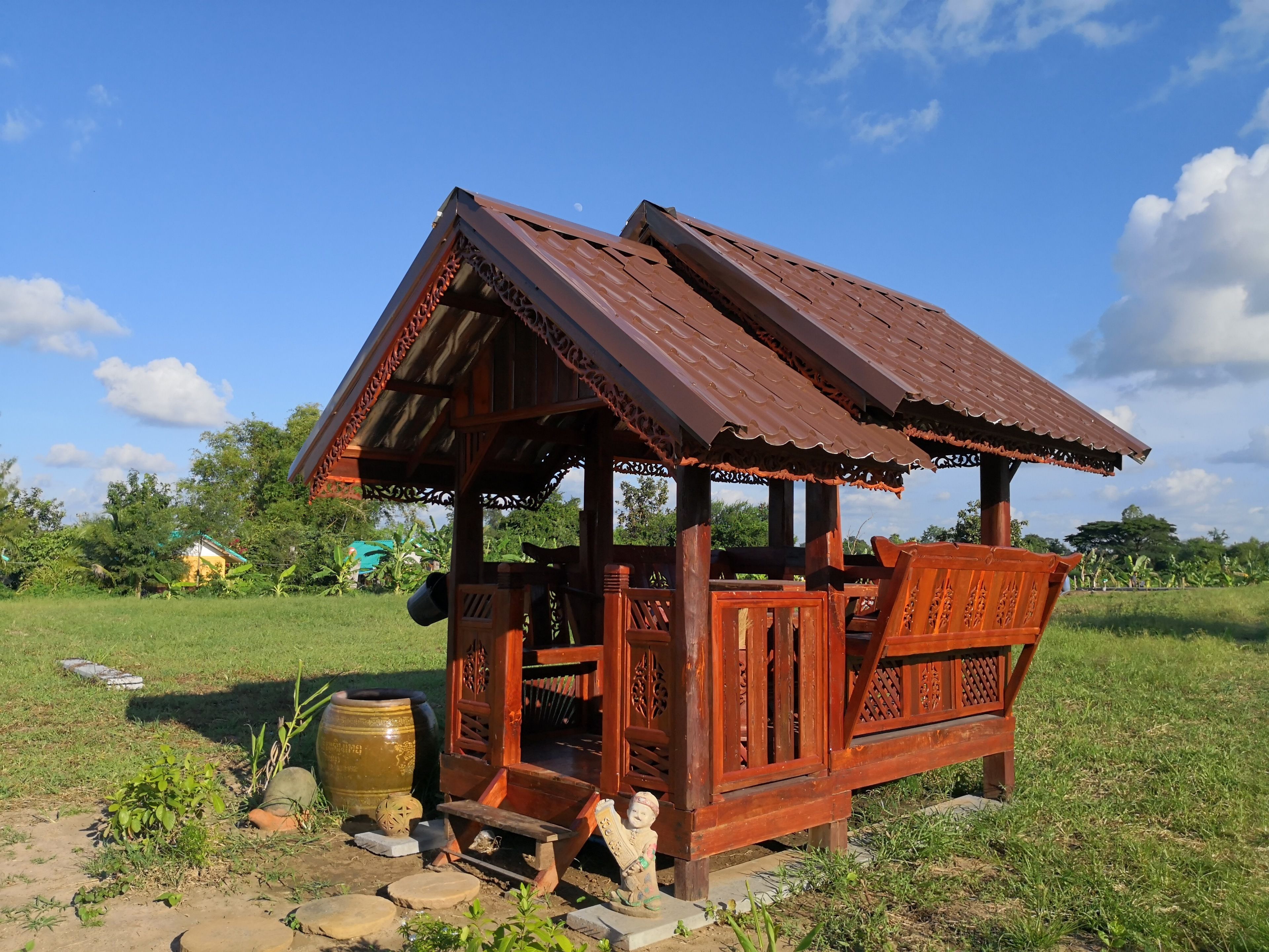 A rustic wooden structure with a sloped roof, a bench, and a decorative pot.