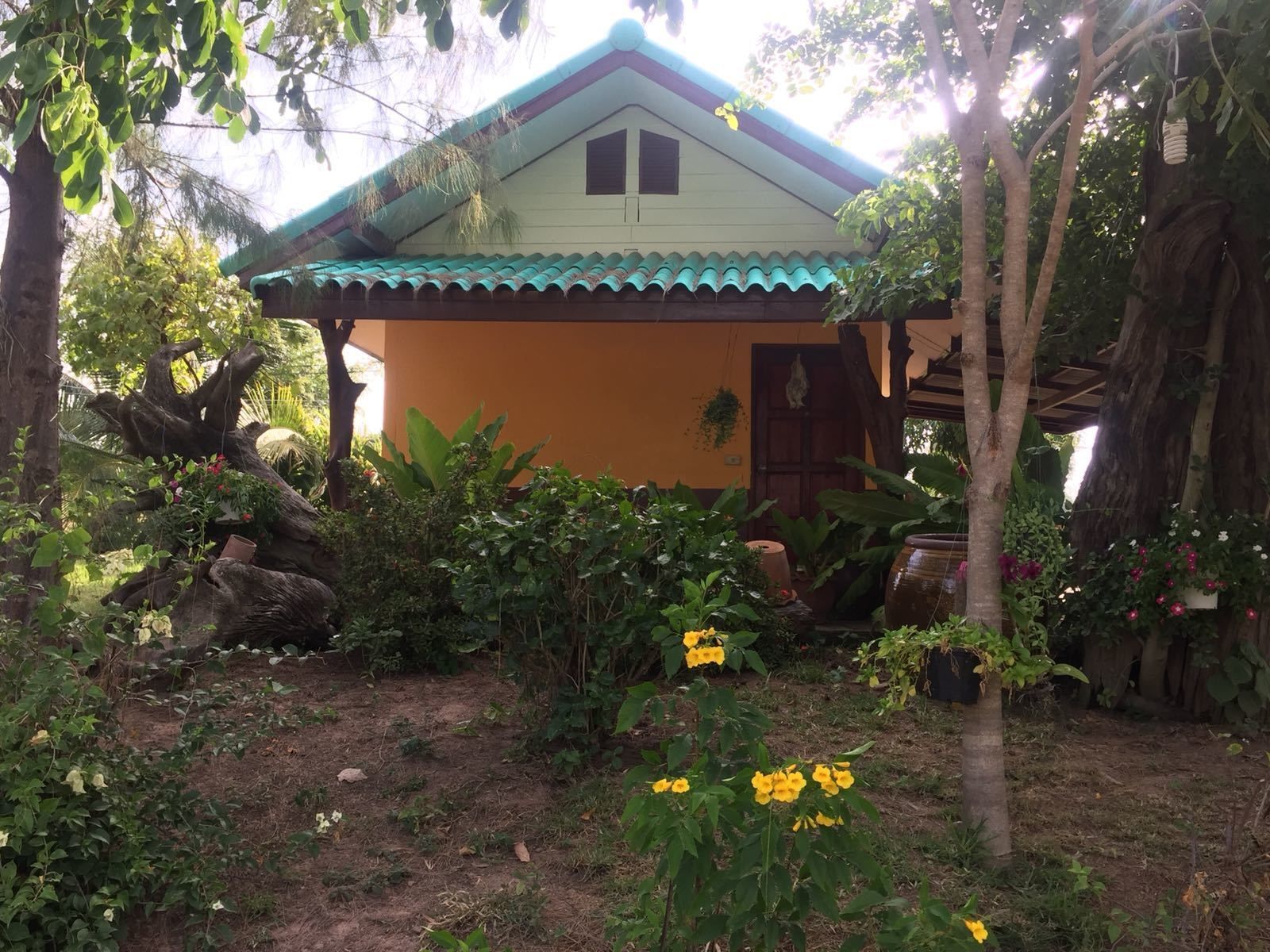 A house with a tiled roof, surrounded by lush greenery and flowering plants.