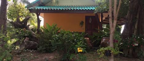 A house with a tiled roof, surrounded by lush greenery and flowering plants.