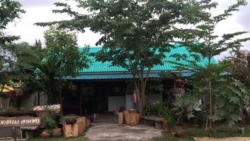 A building with a blue roof and a covered entrance. There are potted plants and a bench outside.