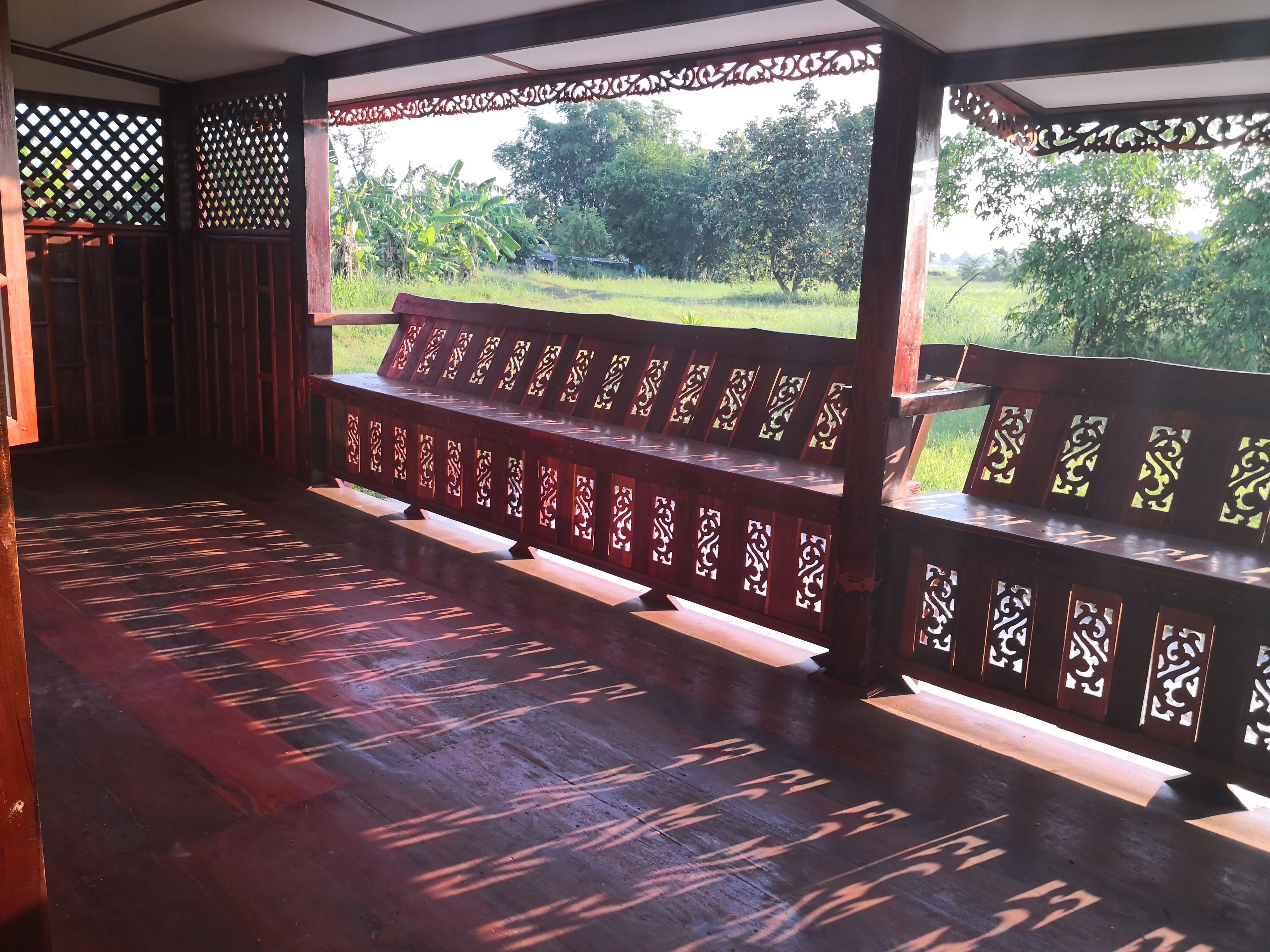 A covered outdoor seating area with wooden benches and lattice panels.