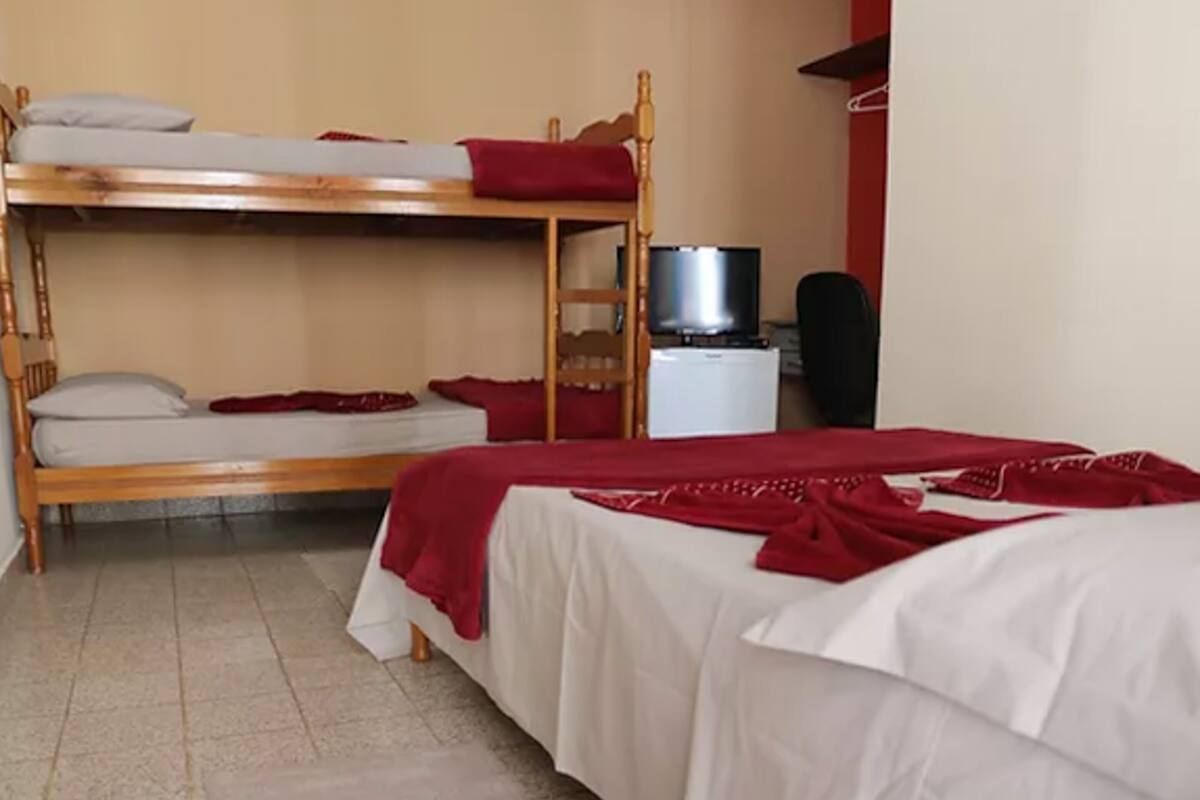 Quarto com duas beliches, televisão e uma pequena escrivaninha.