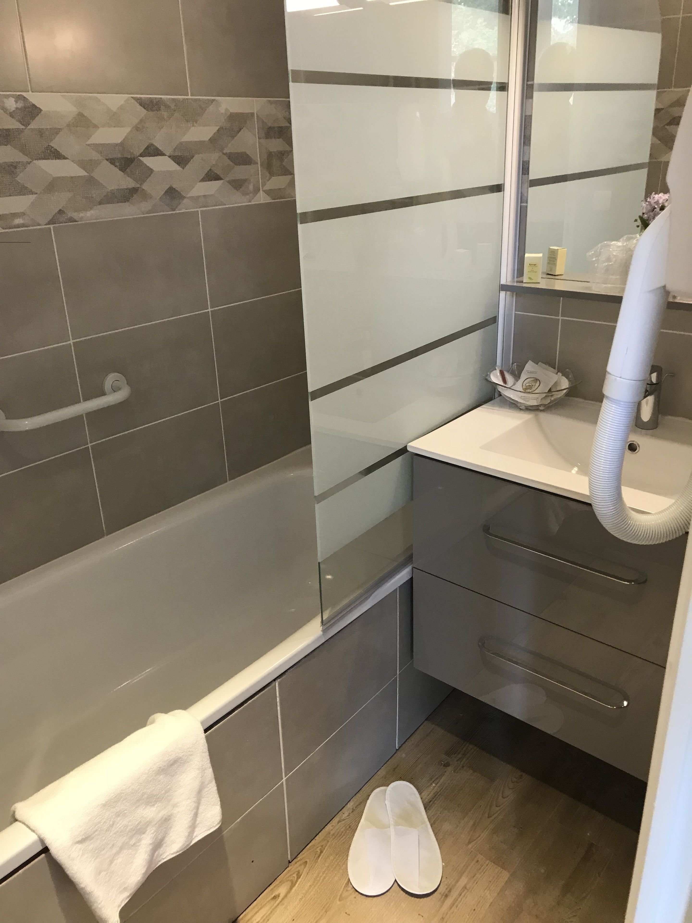 Un baño con bañera, lavamanos, espejo y ducha.