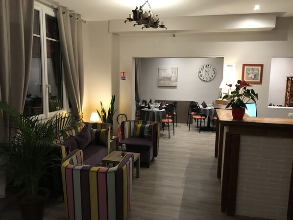 Una sala de estar con sofá, sillas, una mesa de comedor y una cocina al fondo.