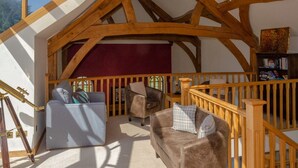 A cozy room with a sloped ceiling, wooden beams, a red curtain, a bookshelf, and a telescope. - Castleview - Newton Steading (Kirriemuir)