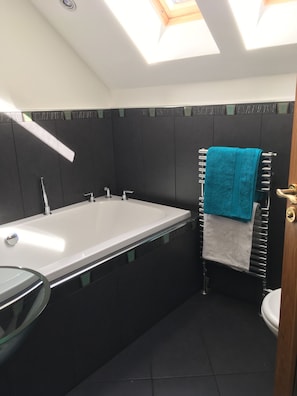A modern bathroom with a bathtub, a toilet, and a glass-enclosed shower area.