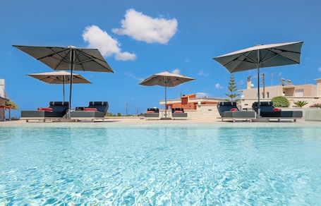 Una piscina al aire libre de temporada, sombrillas