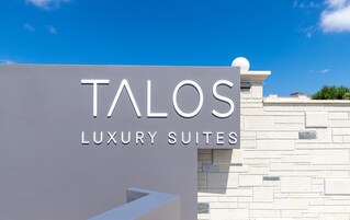 Señal de Talos Luxury Suites con un cielo despejado al fondo.