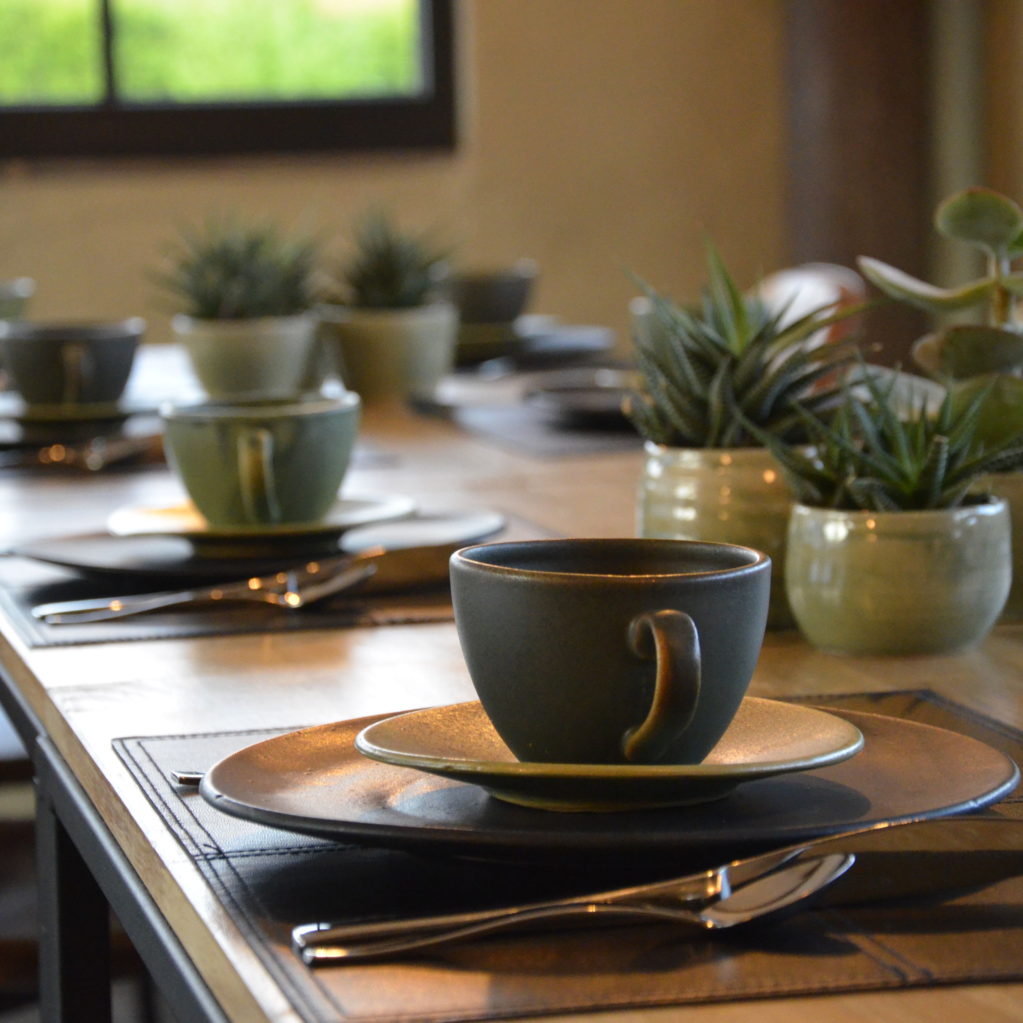 Ein Esstisch mit Tellern, Schüsseln und einer Tasse, komplett mit Besteck.