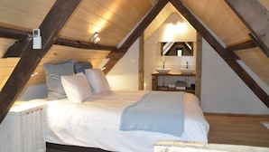 Une chambre à coucher avec un lit, une table de chevet, un miroir et un petit lavabo.