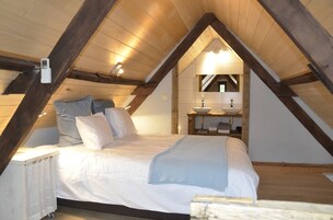 Un dormitorio con una cama, una mesita de noche, un espejo y un lavamanos pequeño.
