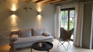 Une pièce avec un canapé gris clair, une table basse noire, un fauteuil moderne et une décoration représentant un crâne de vache accrochée au mur.