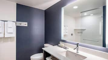 A modern bathroom with a large mirror, a white sink, and a toilet.