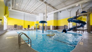 An indoor swimming pool with a blue slide, seating areas, and a high ceiling. - Residence Inn by Marriott Winnipeg (Winnipeg)