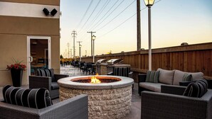 An outdoor patio area with wicker furniture, a stone fire pit, and a wooden fence. - Residence Inn by Marriott Winnipeg (Winnipeg)