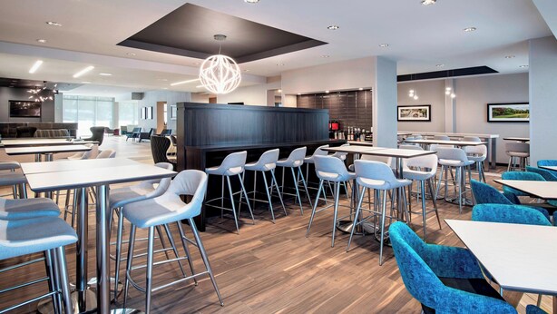 A modern dining area with bar stools, tables, and a central bar area. - Residence Inn by Marriott Winnipeg (Winnipeg)