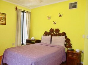 Una habitación con cama, mesita de noche, ventana con cortinas y detalles decorativos en la pared.