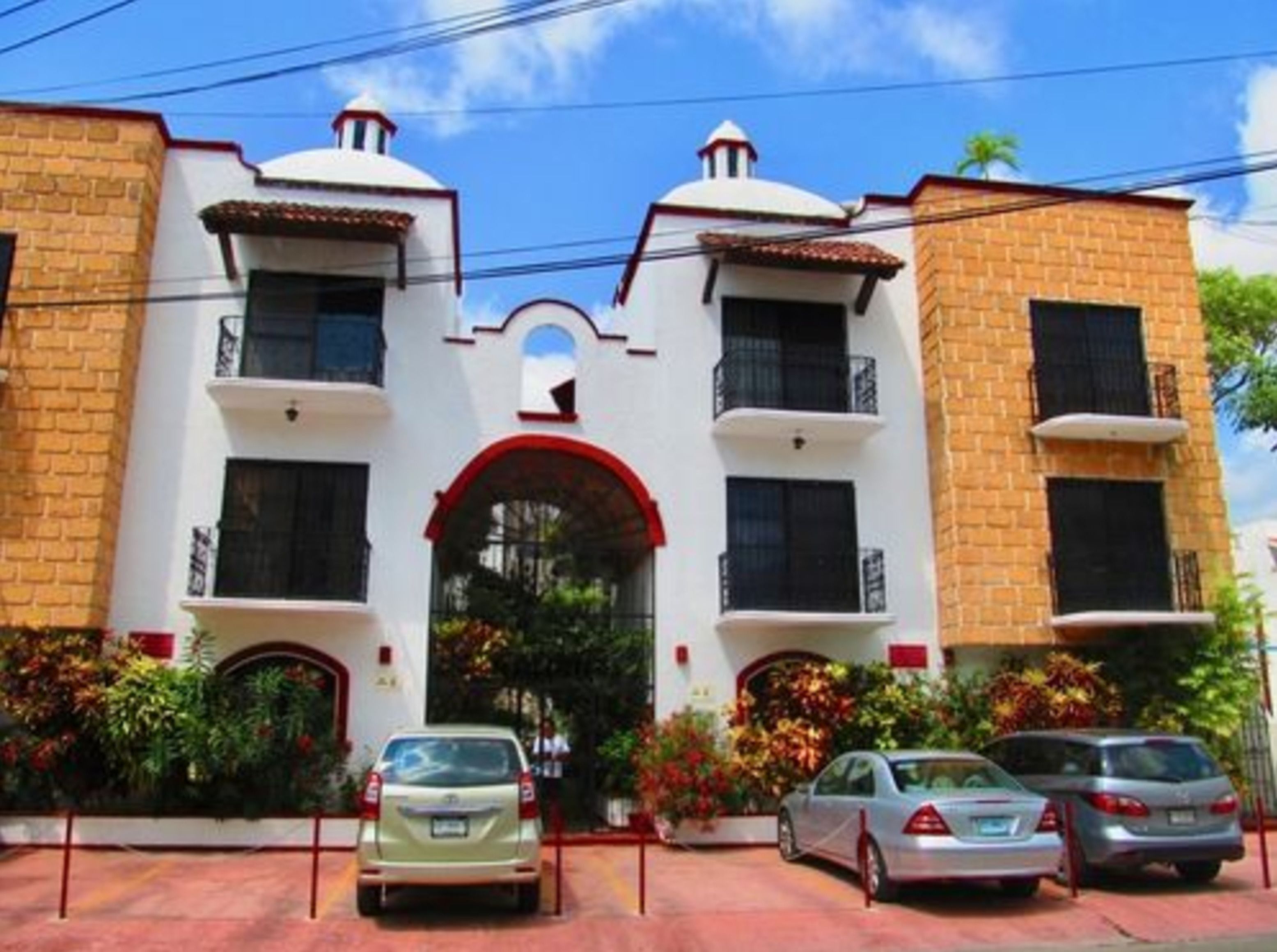 A two-story building with a central archway, multiple balconies, and a red-tiled roof.