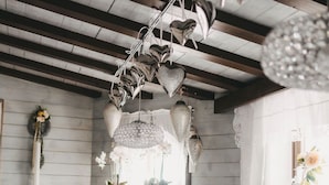 A restaurant interior with wooden beams, hanging heart-shaped light fixtures, and a blue patterned bench. - Hotel Rosenhof Murau (Murau)