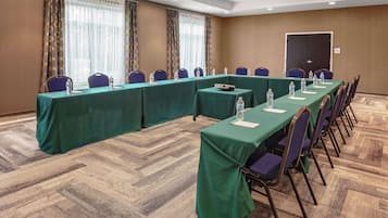 Une salle de conférence avec une longue table, des chaises et des bouteilles d’eau.